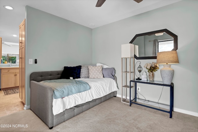 bedroom featuring multiple windows, ceiling fan, light colored carpet, and sink