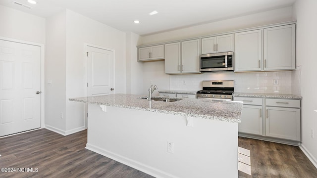 kitchen with gray cabinetry, sink, an island with sink, dark hardwood / wood-style flooring, and stainless steel appliances