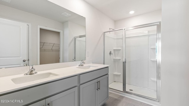 bathroom with hardwood / wood-style floors, vanity, and a shower with door