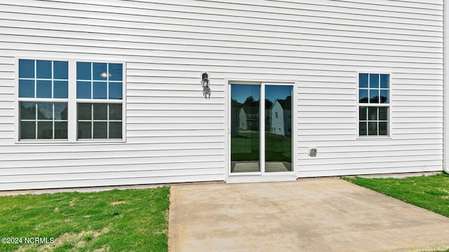 property entrance featuring a patio and a lawn