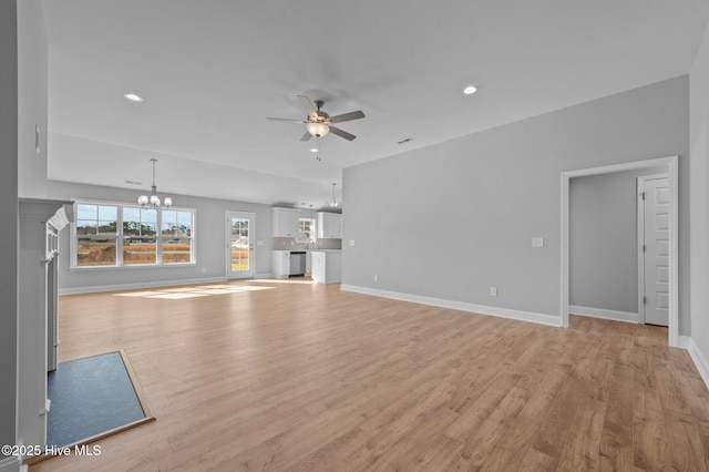 unfurnished living room featuring ceiling fan with notable chandelier and light hardwood / wood-style flooring