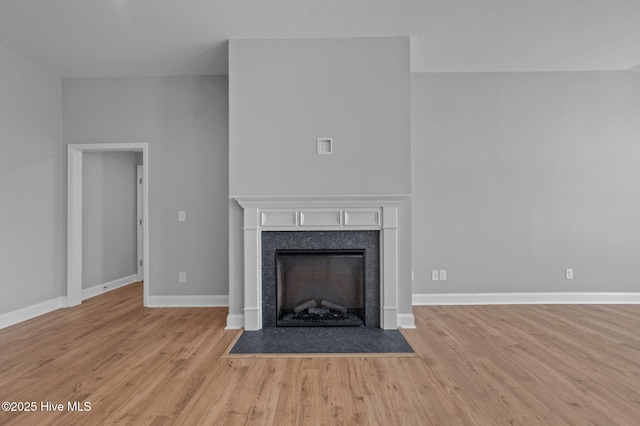 unfurnished living room featuring a high end fireplace and light hardwood / wood-style flooring