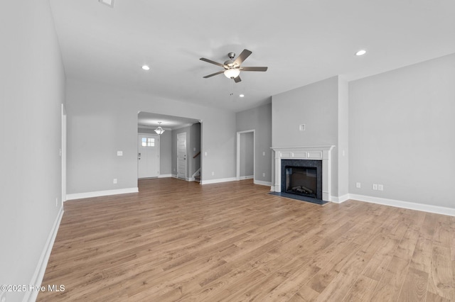 unfurnished living room featuring light wood-type flooring, a high end fireplace, and ceiling fan