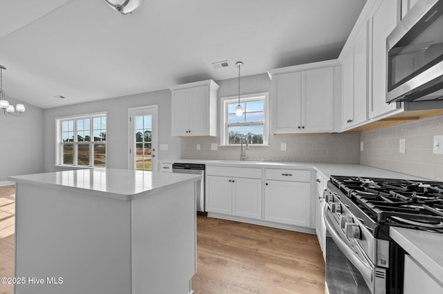 kitchen featuring sink, white cabinets, stainless steel appliances, and pendant lighting