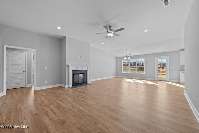 unfurnished living room with ceiling fan with notable chandelier, a high end fireplace, vaulted ceiling, and light hardwood / wood-style flooring