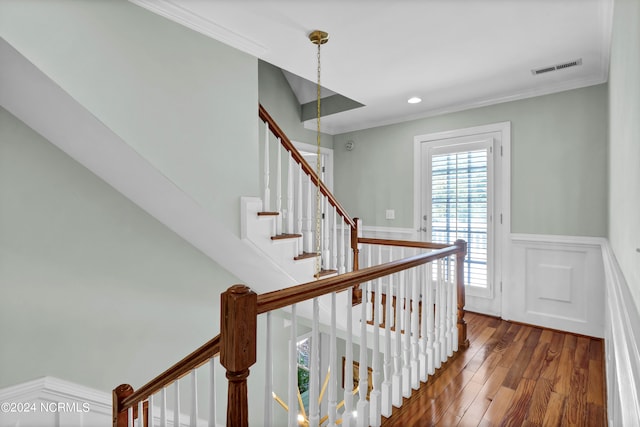 staircase with ornamental molding and hardwood / wood-style floors