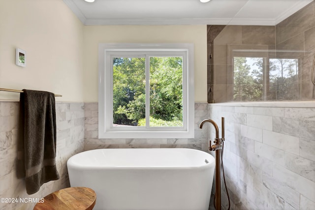 bathroom with a tub to relax in, tile walls, plenty of natural light, and ornamental molding