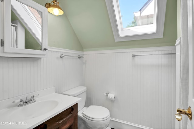 bathroom featuring vanity, vaulted ceiling with skylight, and toilet