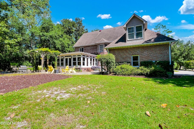 rear view of house featuring a lawn, a patio, and a sunroom