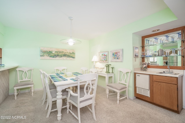 dining area with sink and light colored carpet