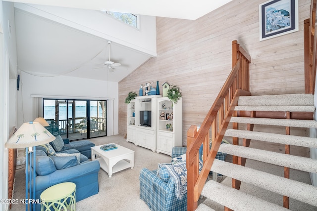 living room with high vaulted ceiling, wood walls, and ceiling fan