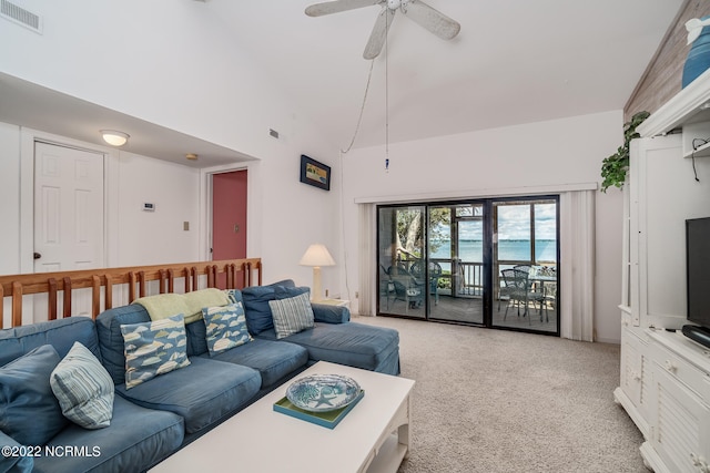 carpeted living room with ceiling fan and vaulted ceiling