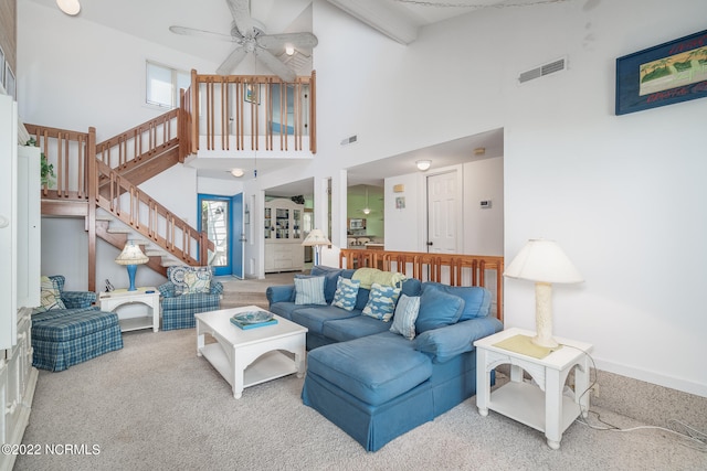 carpeted living room featuring ceiling fan, a towering ceiling, and beamed ceiling