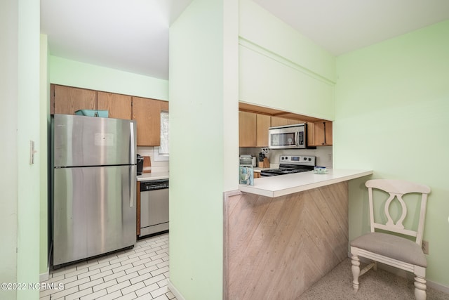 kitchen with appliances with stainless steel finishes, kitchen peninsula, and a kitchen breakfast bar