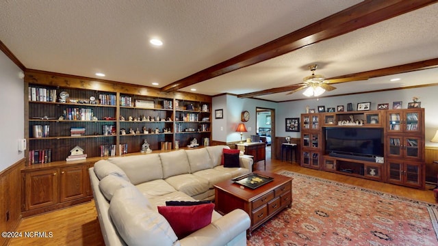 living room with light hardwood / wood-style floors, a textured ceiling, beam ceiling, ceiling fan, and ornamental molding