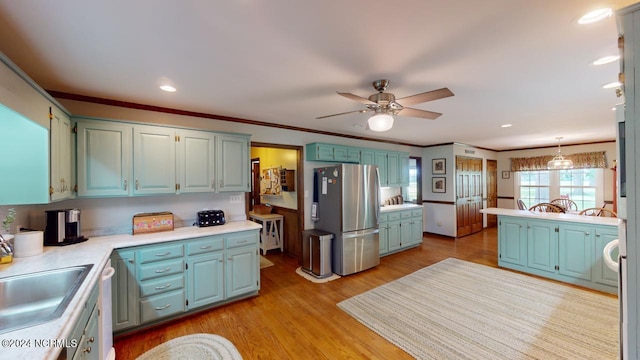 kitchen with pendant lighting, stainless steel appliances, ceiling fan, light hardwood / wood-style flooring, and ornamental molding