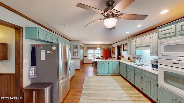 kitchen with light hardwood / wood-style flooring, crown molding, kitchen peninsula, and white appliances