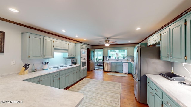 kitchen with white appliances, light wood-type flooring, crown molding, ceiling fan, and sink