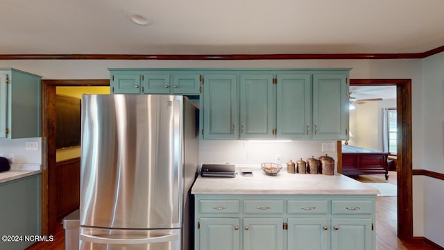 kitchen featuring ceiling fan, stainless steel refrigerator, dark hardwood / wood-style floors, and crown molding