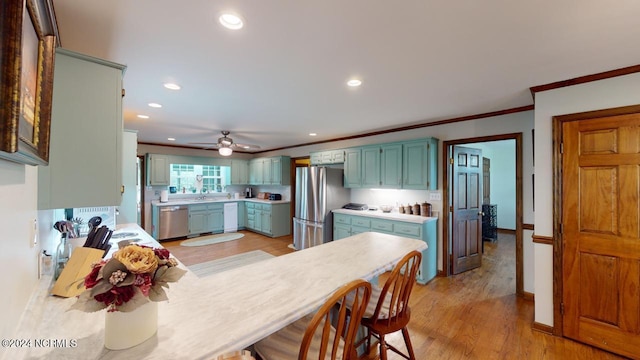 kitchen featuring ceiling fan, sink, ornamental molding, light hardwood / wood-style flooring, and appliances with stainless steel finishes