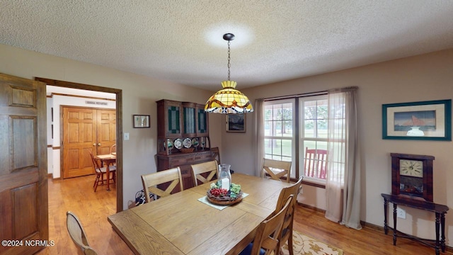 dining area featuring light wood-type flooring and a textured ceiling