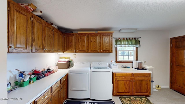 laundry area featuring a textured ceiling, washer and clothes dryer, and cabinets