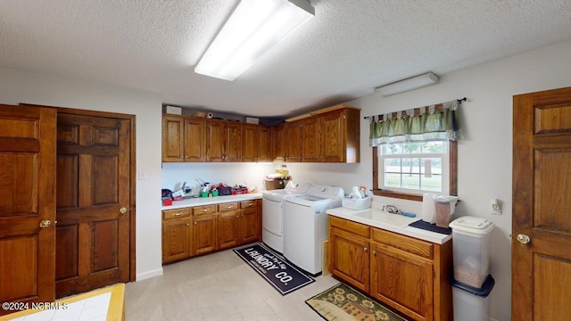 laundry room with cabinets, a textured ceiling, sink, and washing machine and dryer