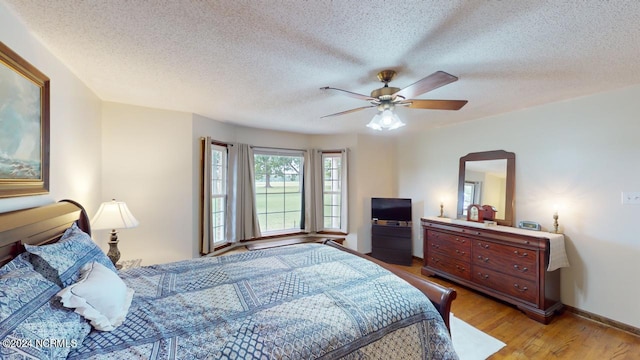 bedroom with light wood-type flooring, a textured ceiling, and ceiling fan