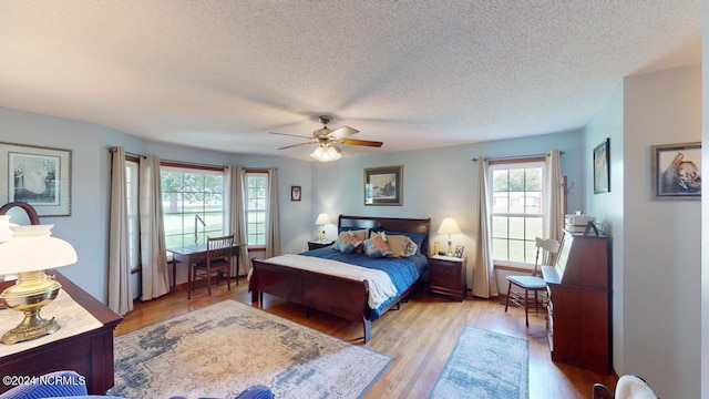 bedroom featuring light hardwood / wood-style floors, ceiling fan, and a textured ceiling