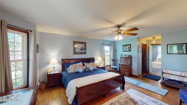 bedroom with multiple windows, connected bathroom, light wood-type flooring, and ceiling fan