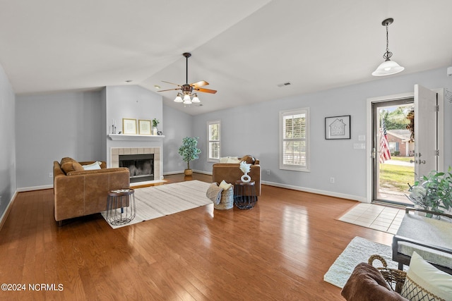 living room with wood finished floors, a healthy amount of sunlight, ceiling fan, and a tiled fireplace