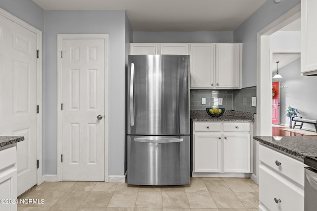 kitchen featuring dark stone countertops, tasteful backsplash, white cabinets, and freestanding refrigerator