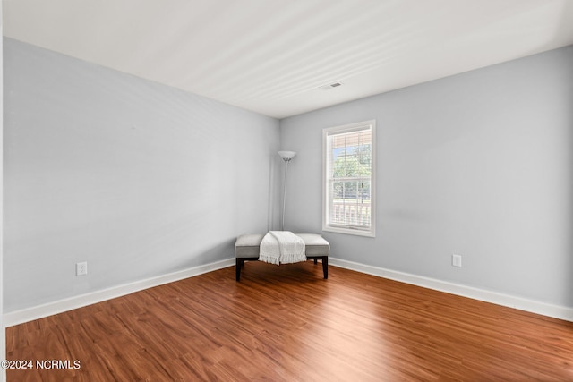 unfurnished room featuring visible vents, wood finished floors, and baseboards