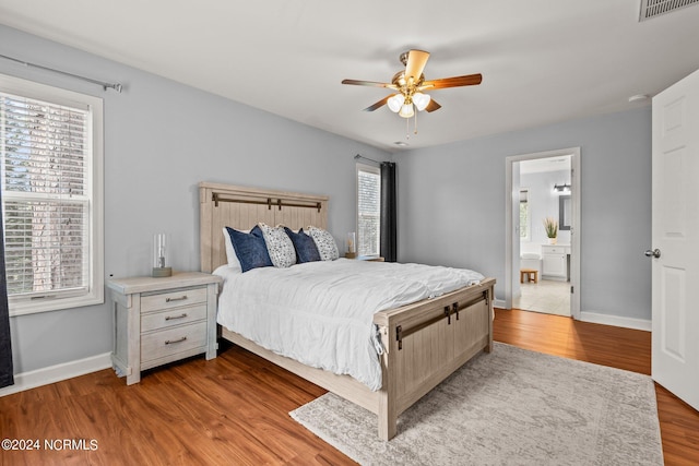 bedroom featuring visible vents, connected bathroom, baseboards, wood finished floors, and a ceiling fan