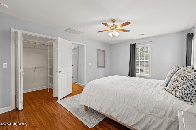 bedroom with visible vents, wood finished floors, a closet, baseboards, and a spacious closet