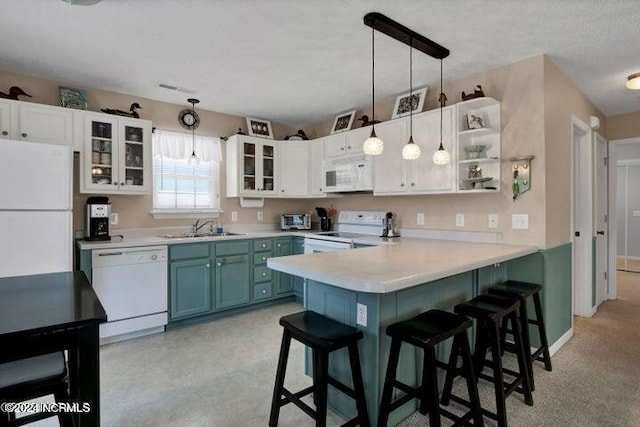 kitchen with white cabinets, hanging light fixtures, white appliances, and a breakfast bar