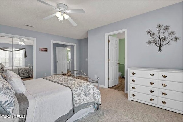 carpeted bedroom featuring ensuite bath, ceiling fan, and a textured ceiling