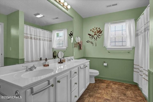 bathroom with vanity, a wealth of natural light, a textured ceiling, and toilet