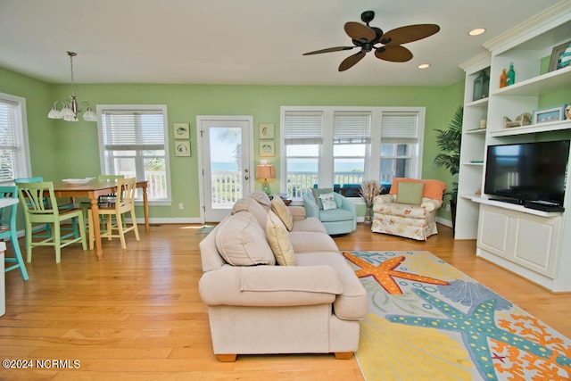 living room with ceiling fan with notable chandelier and light wood-type flooring