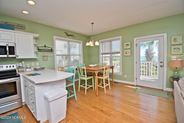 kitchen with appliances with stainless steel finishes, a wealth of natural light, light hardwood / wood-style flooring, and white cabinets