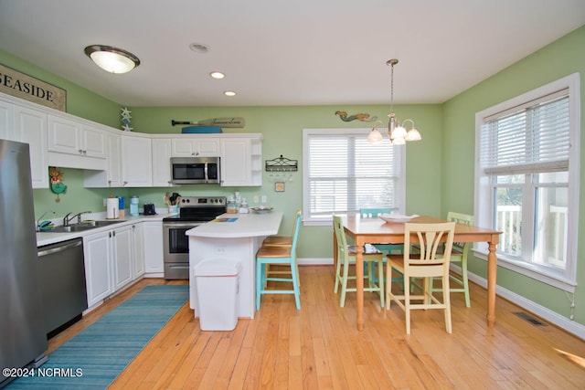 kitchen with stainless steel appliances, hanging light fixtures, a wealth of natural light, and a kitchen breakfast bar