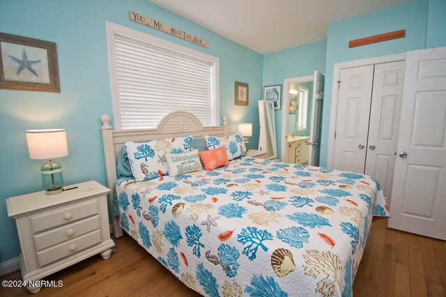 bedroom with a closet, ensuite bath, and dark wood-type flooring