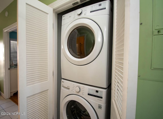 laundry area featuring stacked washer and clothes dryer and tile patterned flooring