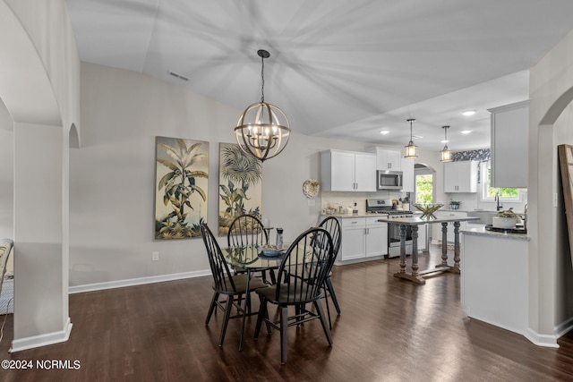 dining room with a chandelier, dark hardwood / wood-style floors, lofted ceiling, and sink