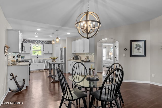 dining area with a notable chandelier, sink, and dark wood-type flooring