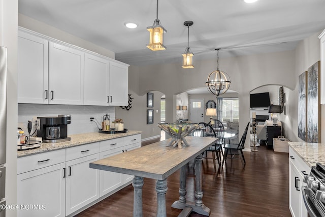 kitchen with light stone countertops, dark wood-type flooring, white cabinetry, stainless steel electric range oven, and hanging light fixtures