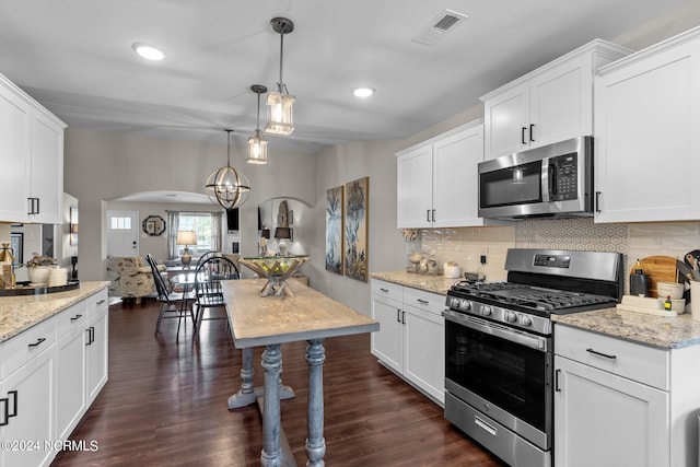 kitchen with dark wood-type flooring, white cabinetry, hanging light fixtures, and stainless steel appliances