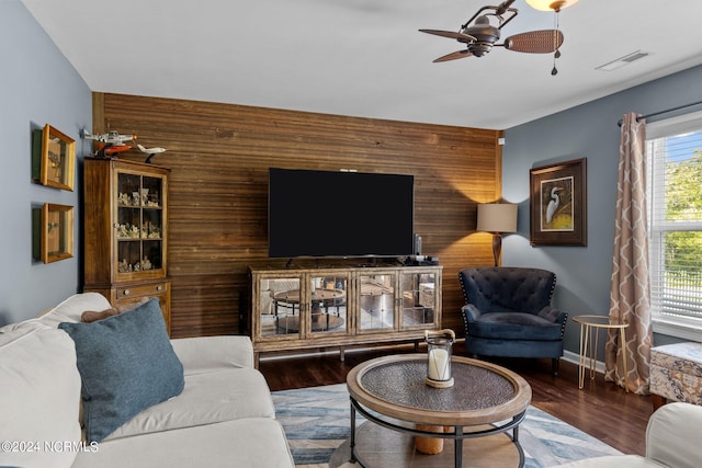 living room with wooden walls, ceiling fan, and dark hardwood / wood-style floors