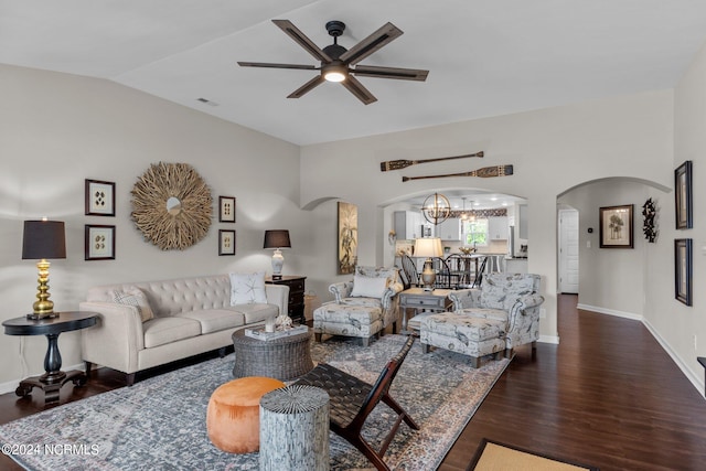 living room with ceiling fan with notable chandelier, dark hardwood / wood-style floors, and vaulted ceiling