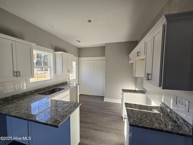 kitchen featuring kitchen peninsula, white cabinetry, dark hardwood / wood-style flooring, and backsplash